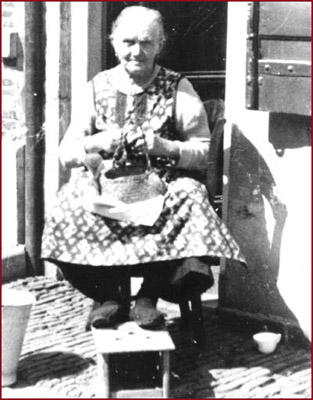 Mevr. Schoonheid schilt aardappelen voor haar huis in de Bergstraat (1935)